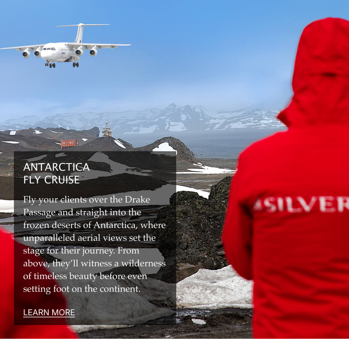 A person in a red jacket gazes at a snowy, mountainous landscape with an airplane flying above.